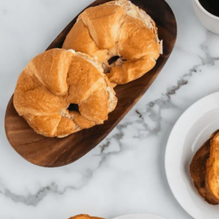 Croissants sliced in half lengthwise on a wooden cutting board