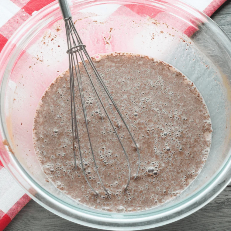 Eggs, milk, cinnamon, and vanilla whisked into a smooth custard in a shallow bowl