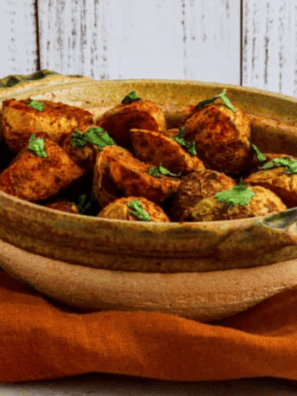 Crispy air fryer curry potatoes with golden edges in a white bowl, topped with fresh cilantro