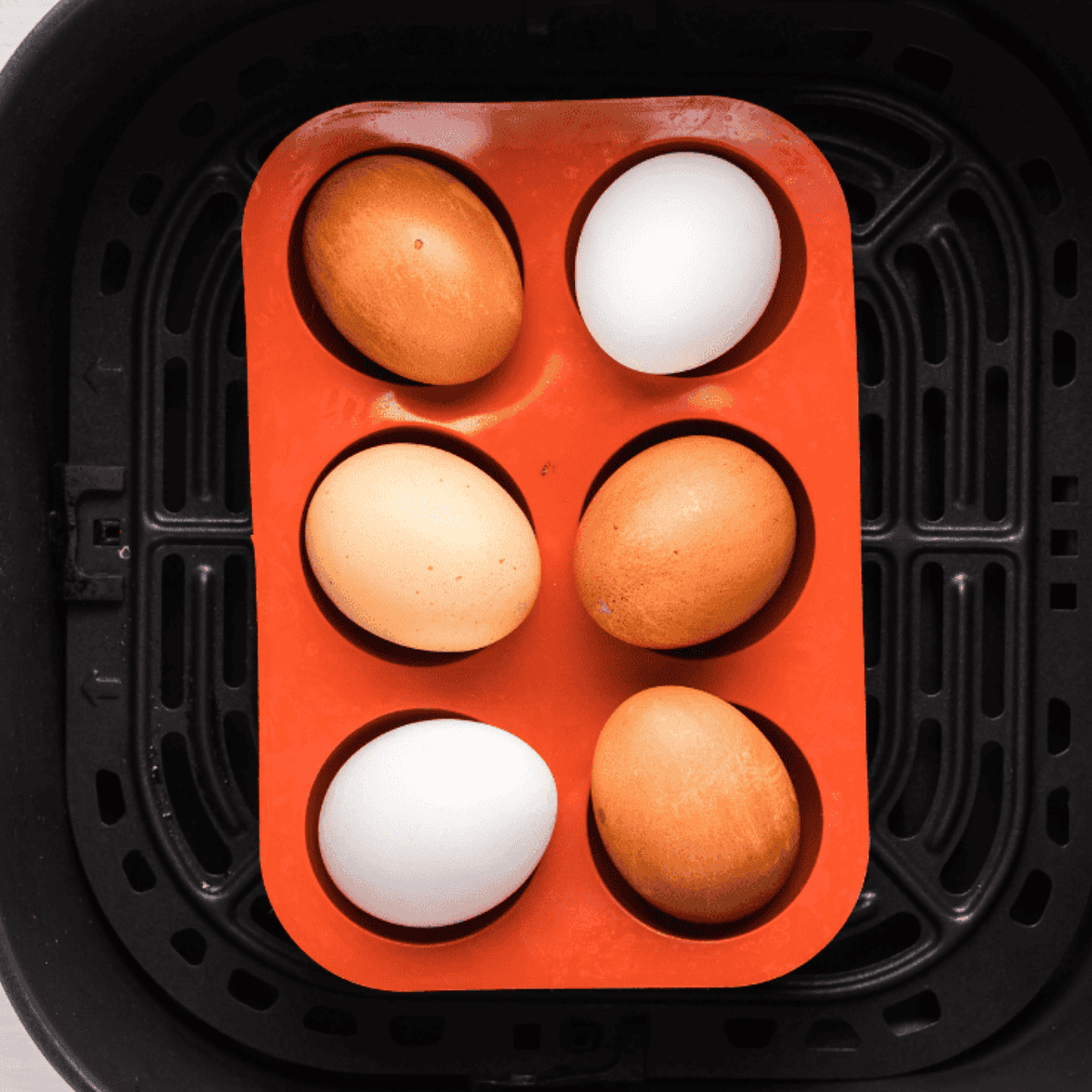 Eggs placed in an air fryer basket, set to 250°F for 15 minutes using the air fryer setting to make hard-boiled eggs.