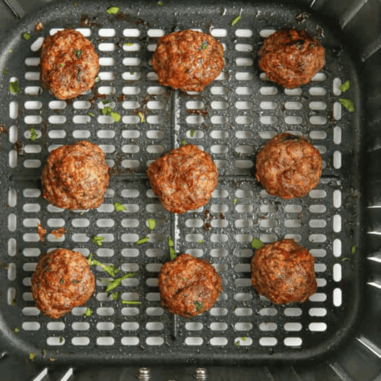Adding meatballs to the air fryer basket, lightly sprayed with olive oil for even cooking.