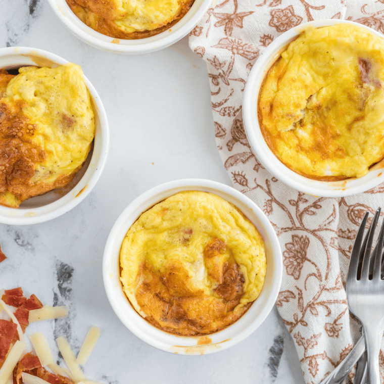 Fork pulling a forkful of fluffy eggs and melted cheddar from a freshly cooked air fryer cheesy egg mug omelet