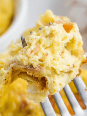 Fluffy air fryer mug omelet with melted cheddar cheese and scallions in a white ramekin