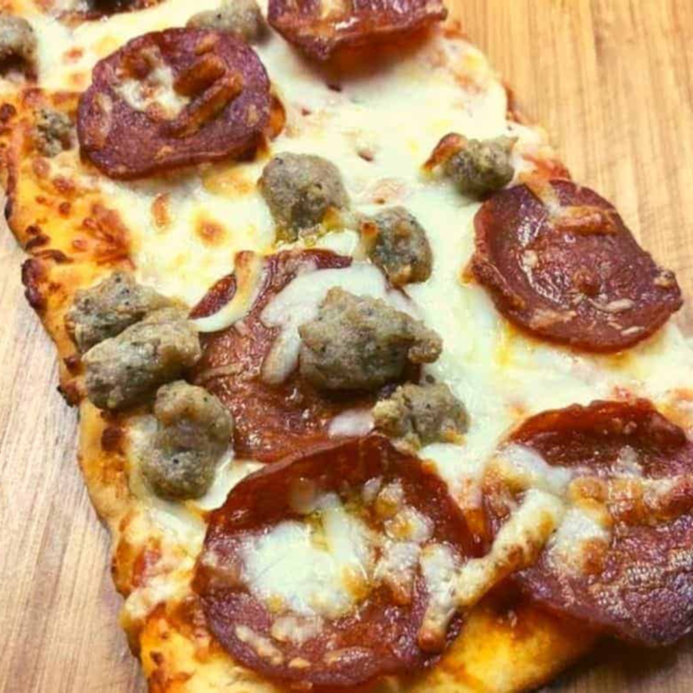 "Air Fryer Pepperoni and Sausage Flatbread Pizza topped with melted cheese, crispy pepperoni slices, and savory sausage, freshly cooked and served on a wooden cutting board."