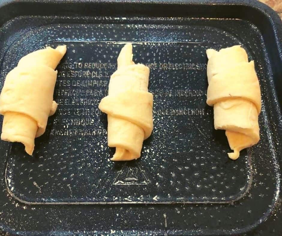 Place the rolled up crescent dough onto the air fryer tray or in the basket (both sprayed with olive oil, so they do not stick)