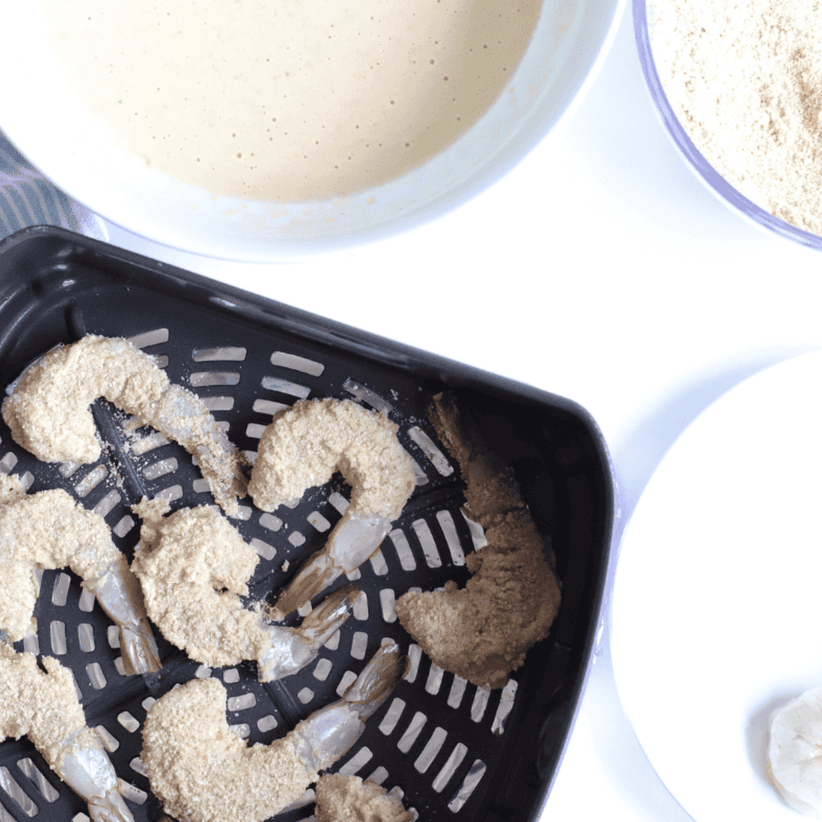 Air fryer basket sprayed with oil and filled with breaded shrimp in a single layer, not touching.