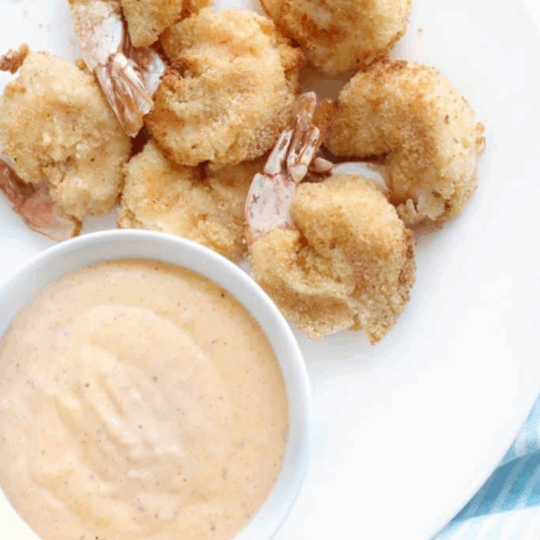 Golden, crispy Arthur Treacher’s fried shrimp served with tartar sauce on a plate.