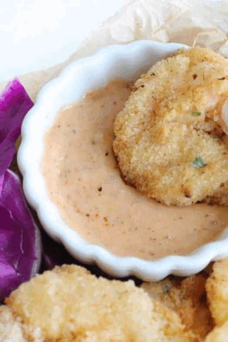 Golden crispy fried shrimp plated with tartar sauce and lemon wedges.