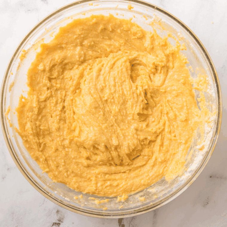 Combining wet and dry ingredients in a mixing bowl to make homemade Boston Market-style cornbread batter.