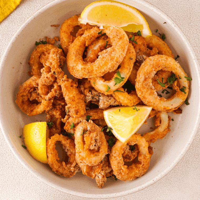 Plate of crispy Carrabba’s Calamari served with lemon wedges and a side of marinara sauce.