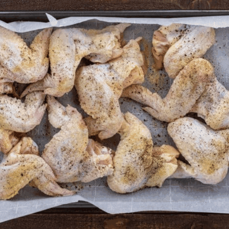 Seasoned raw chicken wings placed in the air fryer basket