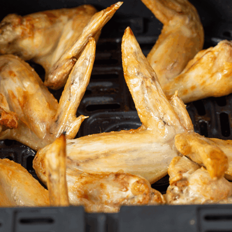 Golden brown copycat Domino’s plain wings on a serving plate with dipping sauces nearby.