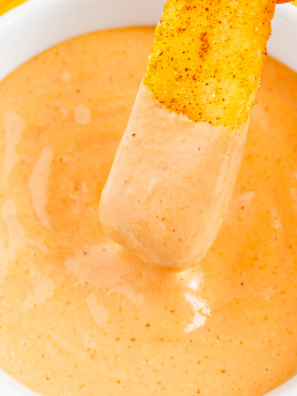 French fry being dipped into a bowl of copycat Raising Cane’s sauce.