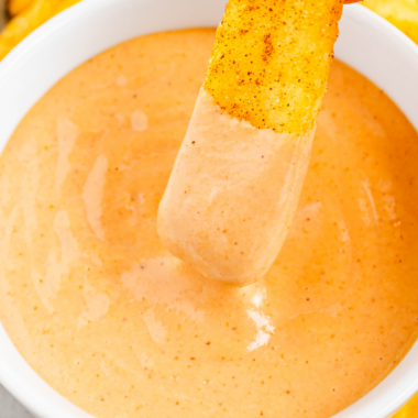 French fry being dipped into a bowl of copycat Raising Cane’s sauce.
