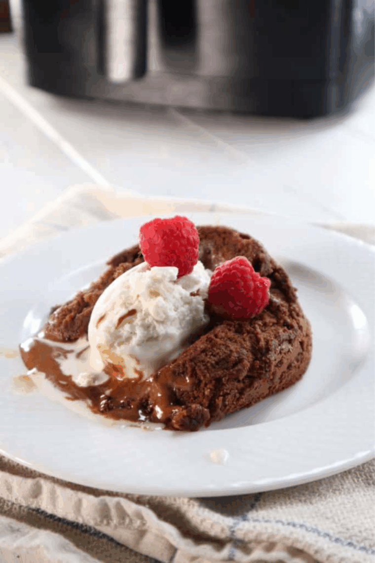 Plate of lava cake with whipped cream and fruit on a white plate.