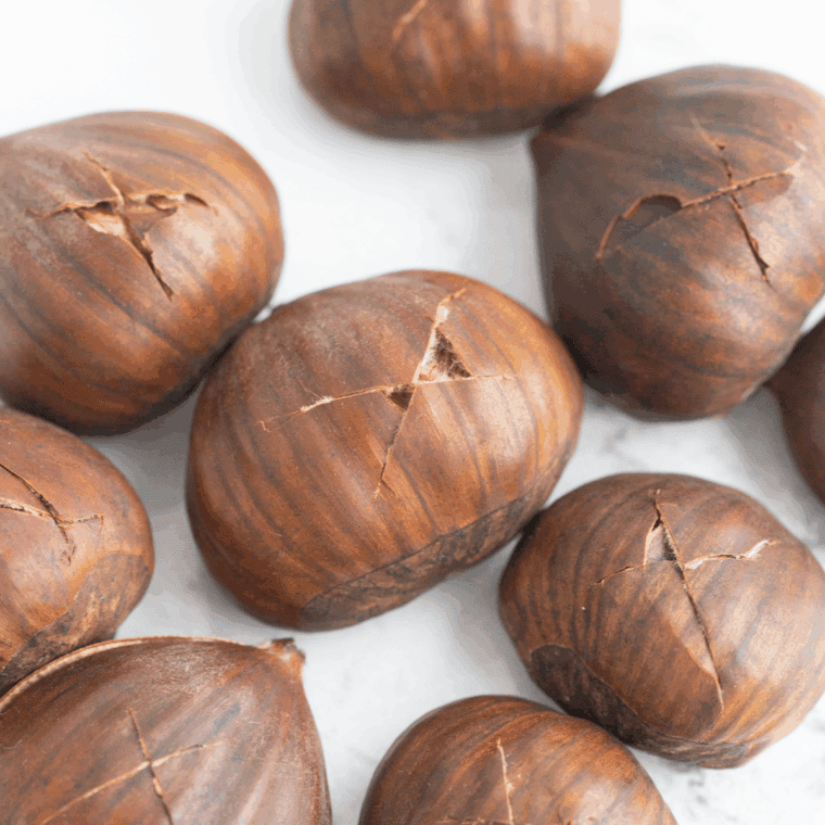 Scoring each chestnut shell with a sharp knife before air frying.