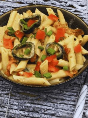 Creamy Instant Pot Cajun Chicken Alfredo served with penne pasta, sliced chicken, parmesan cheese, and Cajun seasoning in a white bowl.