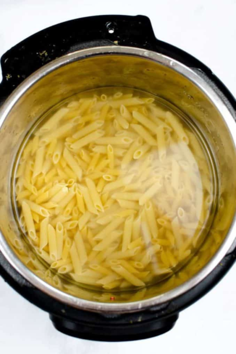 Instant Pot with penne pasta and water inside, ready to cook under manual high pressure for 8 minutes.