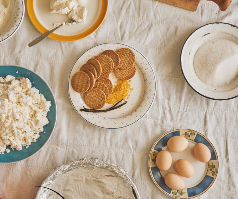 "Ingredients for Instant Pot Holiday Cheesecake including cream cheese, sugar, eggs, sour cream, vanilla extract, and graham cracker crumbs, arranged on a kitchen counter."