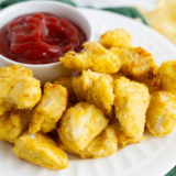 Air fryer Chick-Fil-A style chicken nuggets in a basket, golden brown and crispy with dipping sauce on the side.