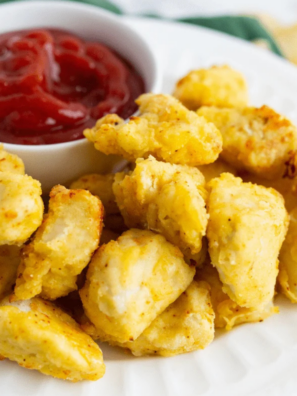 Air fryer Chick-Fil-A style chicken nuggets in a basket, golden brown and crispy with dipping sauce on the side.