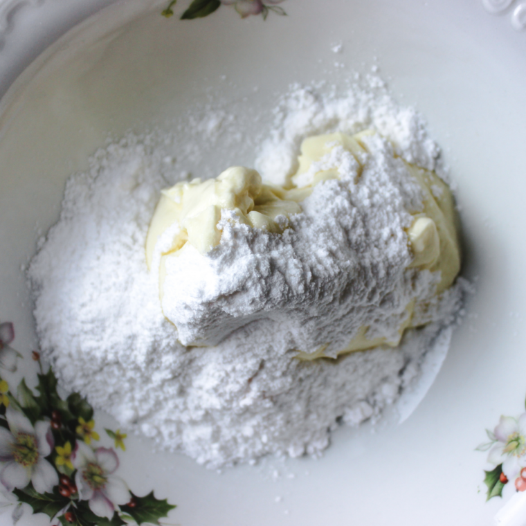 Cream cheese and powdered sugar beaten into smooth orange frosting in a bowl