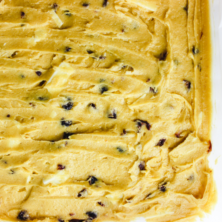 Cranberry bliss bar batter spread evenly in a parchment lined pan inside the air fryer basket