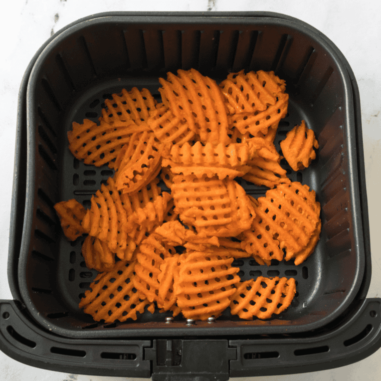 Frozen sweet potato fries in the air fryer basket.