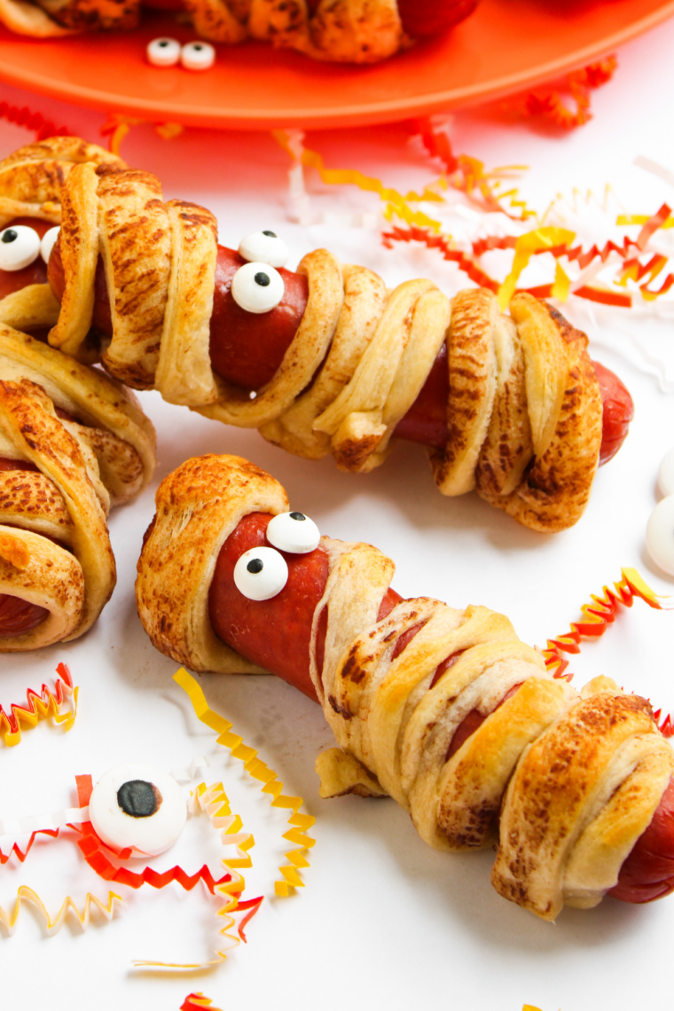 Air fryer mummy hot dogs wrapped in crescent dough with candy eyes, cooked until golden brown and crispy for Halloween.