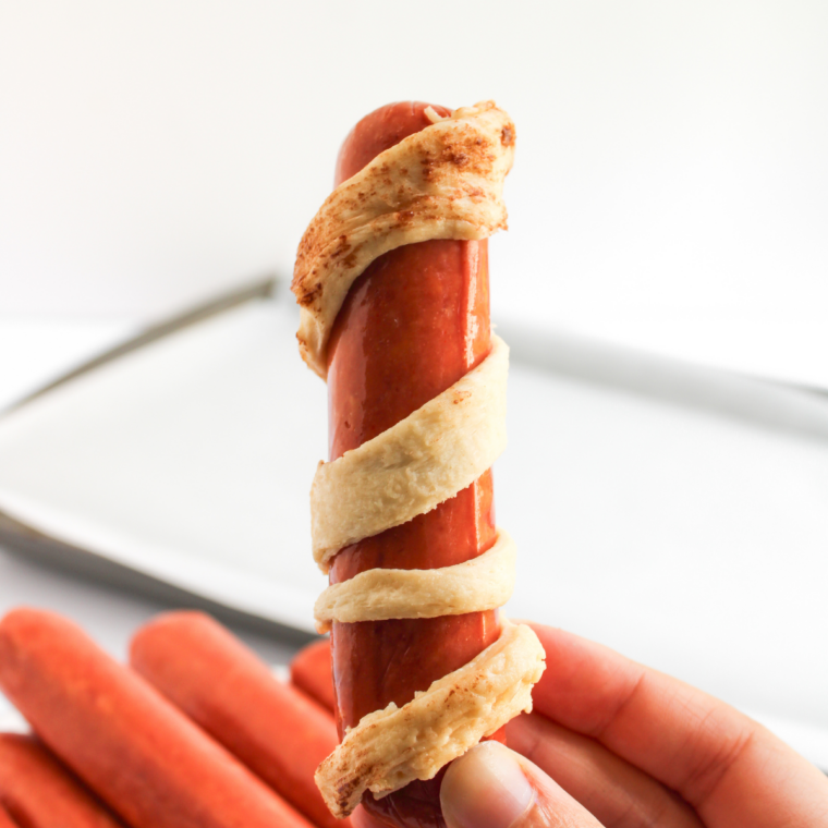 Hot dogs wrapped in crescent dough strips with gaps left for mummy face.
