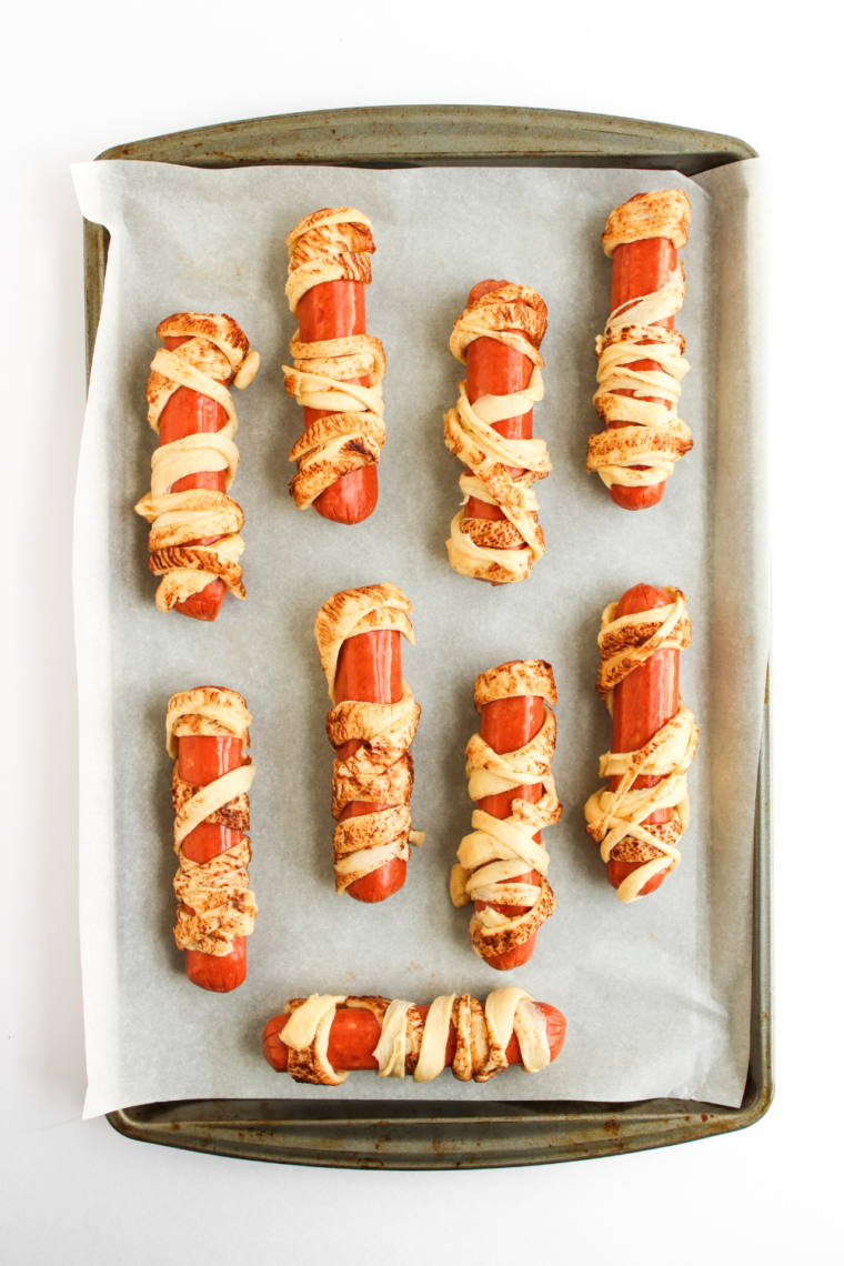 Mummy hot dogs placed in air fryer basket spaced apart for even cooking.