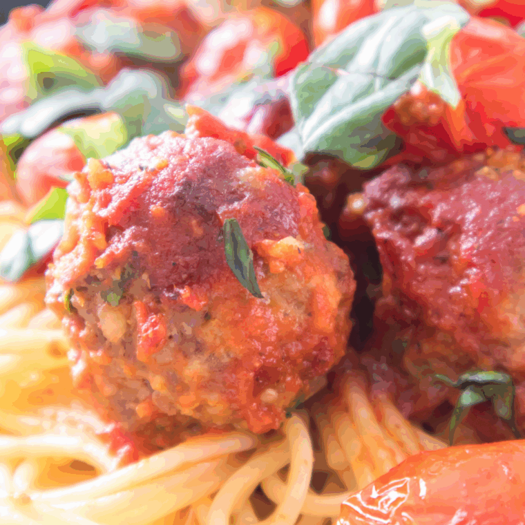 Golden-brown Bobby Flay meatballs served with marinara sauce and parsley