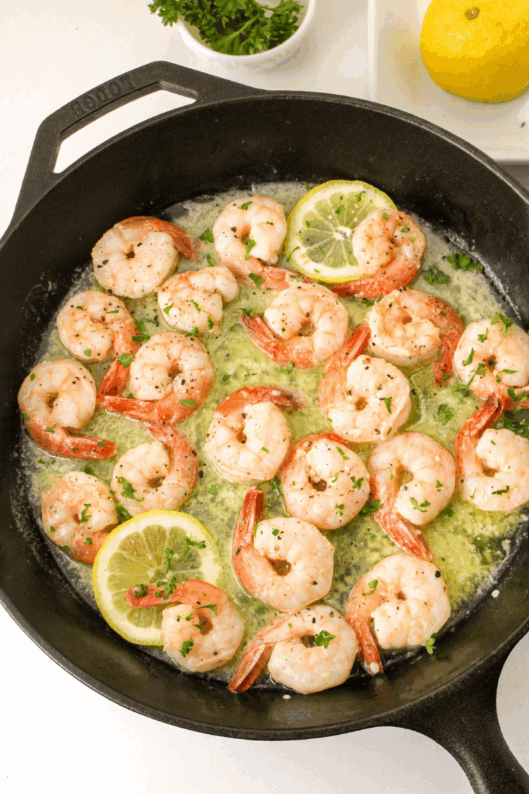 Shrimp turning pink as they cook in a hot skillet.