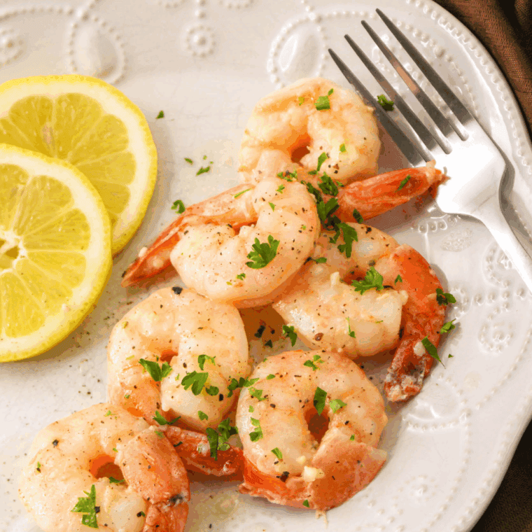 Shrimp scampi garnished with parsley, served over pasta with crusty bread on the side.