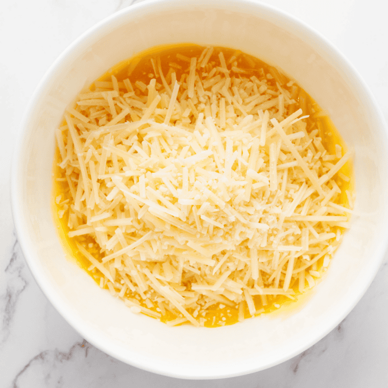 Whisking eggs, Pecorino Romano, and Parmesan cheese in a glass bowl for Instant Pot carbonara sauce.