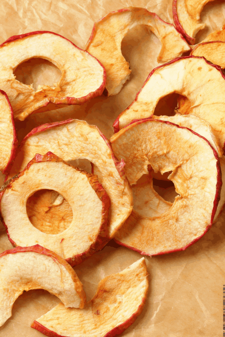 Thinly sliced apple chips crisping in an air fryer basket, golden brown and ready to enjoy.