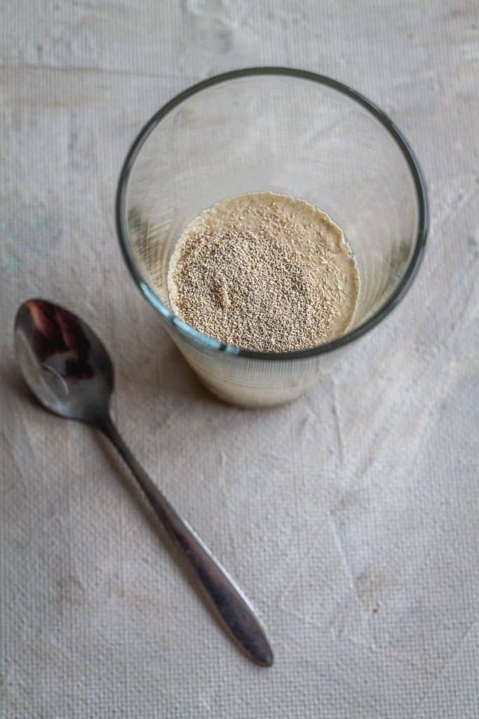 In a cup or a glass combine yeast, sugar and about 1/3 cup lukewarm water. Mix well and set aside for 5 minutes.