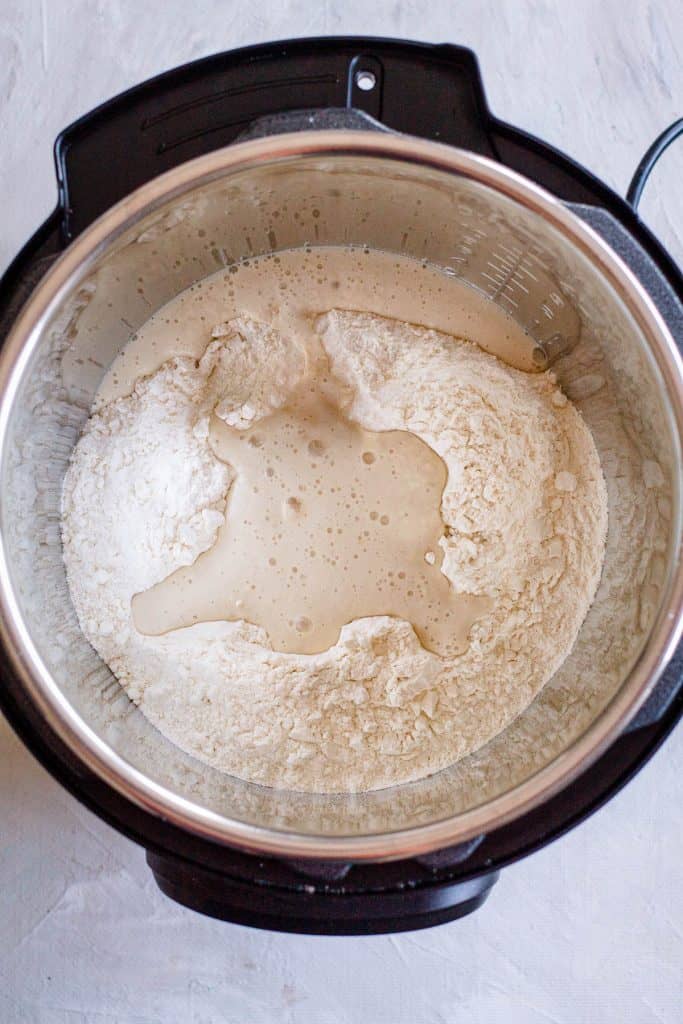 In the Instant Pot combine the flour, salt and the yeast mixture. Start mixing with a wooden spoon. Add the olive oil and continue stirring. Little by little add the remaining water. Mix until a soft and not too sticky dough forms. Knead it with a hand shortly, to make sure all the flour is evenly absorbed.
