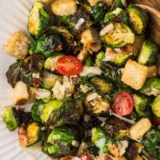 Lazy Dog Brussels sprouts recipe in a cast iron skillet with crispy croutons, capers, and grated Romano