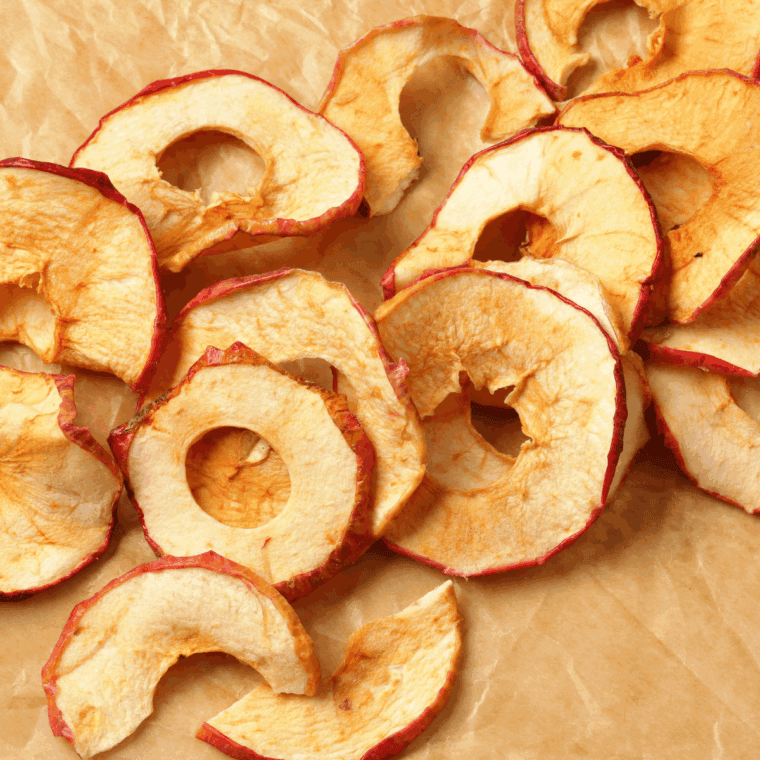Air fryer apple chips arranged in a bowl, golden brown and crispy, sprinkled with cinnamon.