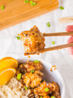 Slow cooker orange chicken served over white rice with sesame seeds and green onions