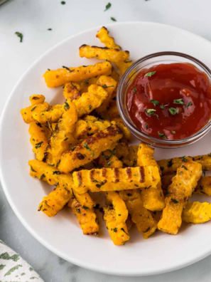 Plate of crispy Air Fryer Butternut Squash Fries seasoned to perfection with a side of garlic thyme aioli.