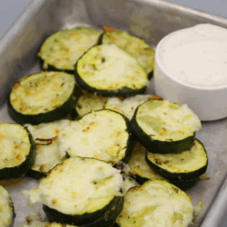 Crispy air-fried zucchini slices topped with melted cheddar cheese, served on a plate ready to enjoy.