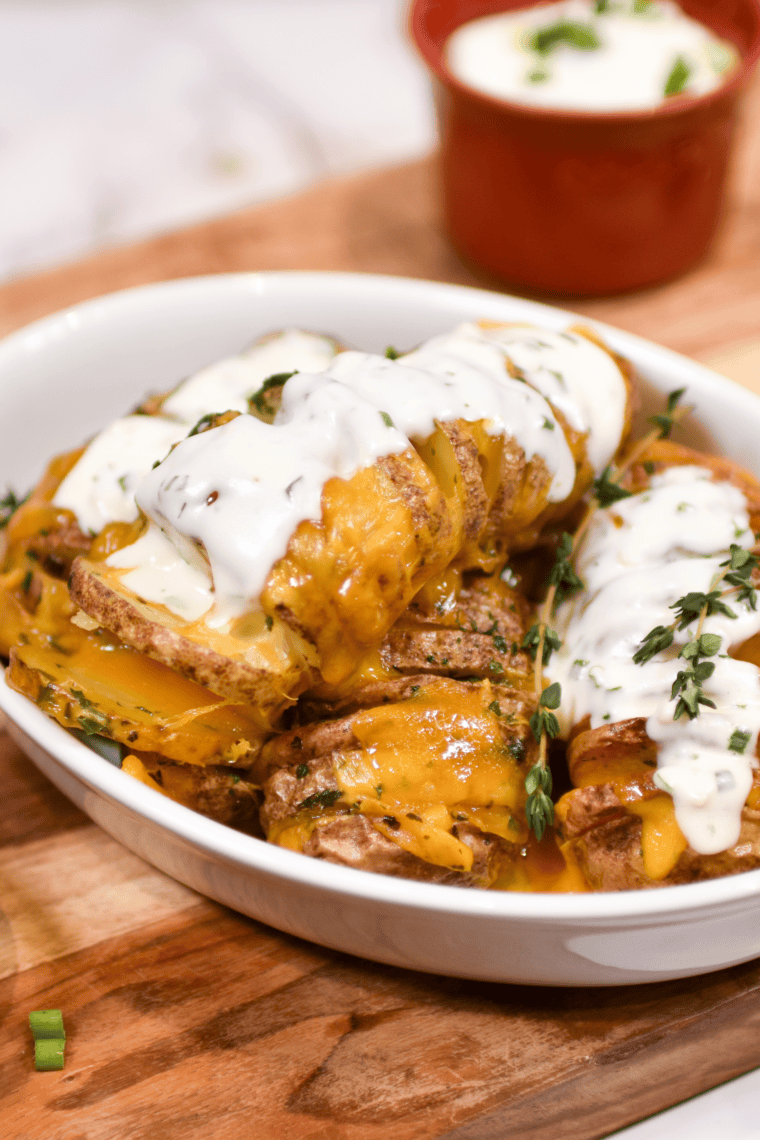 Plated air fryer Hasselback potatoes with melted cheddar in the slices and sour cream on the side