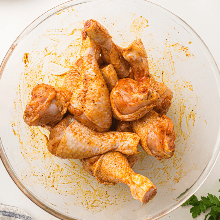 Preheating air fryer and seasoning frozen chicken drumsticks.