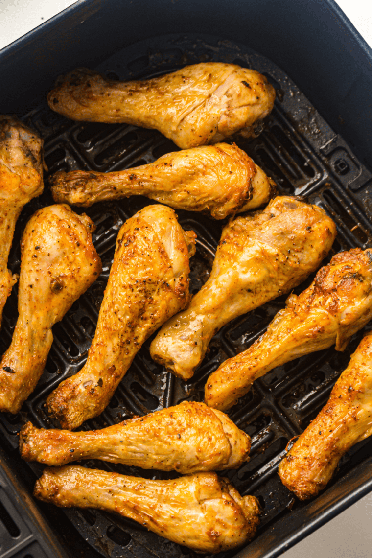 Frozen chicken drumsticks in air fryer cooking process for crispy and juicy results.