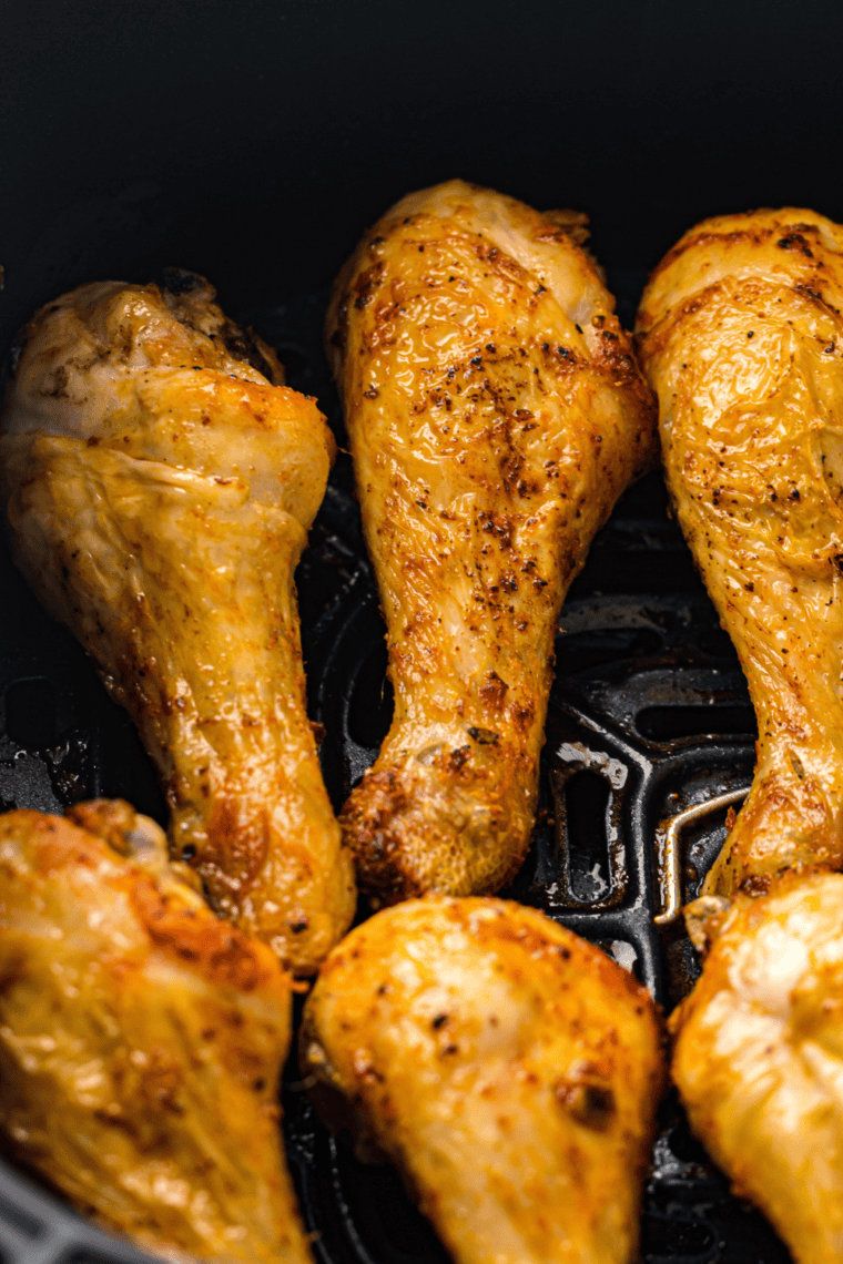 Frozen chicken drumsticks in air fryer cooking process for crispy and juicy results.