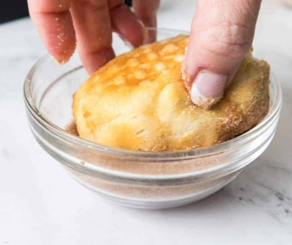 process shot: dipping an air fryer jelly donut into the cinnamon sugar