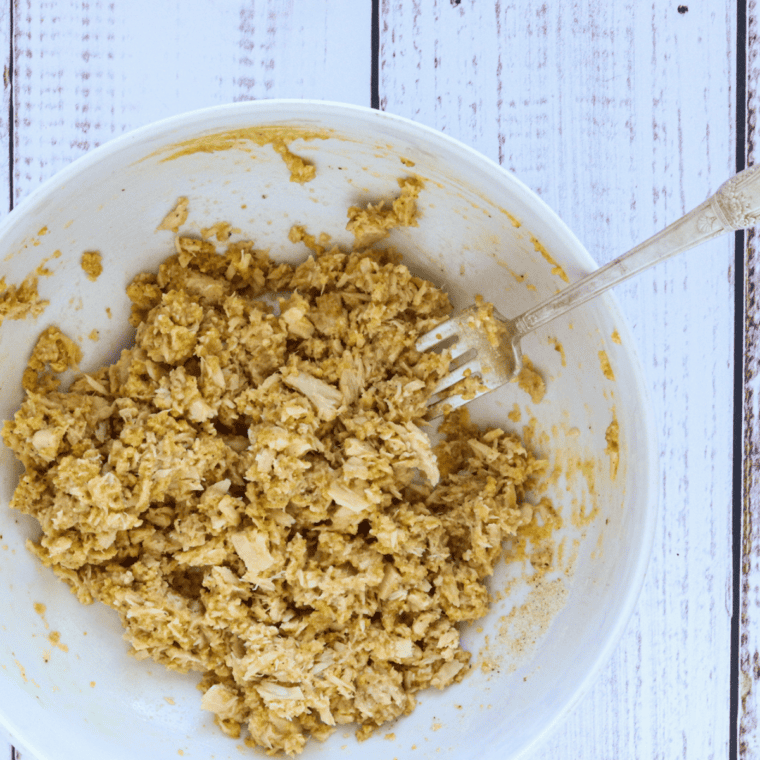 Cooked lobster meat mixed with bread crumbs and Cajun seasoning in a glass bowl