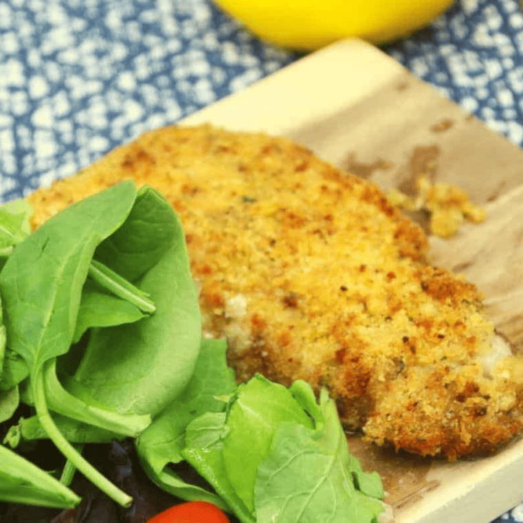 Plate of Air Fryer Parmesan Crusted Cod fillets, golden and crispy, served with a lemon wedge and fresh parsley.